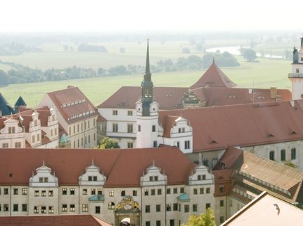 Das Schloss Hartenfels in Torgau ist von oben zu sehen. Hinter dem Schloss fließt der Fluss Elbe und Wiese und Wald befinden sich auf der anderen Flussseite. 