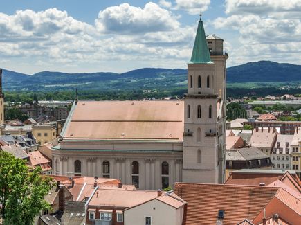 Der Ausblick vom Johanneum in Zittau in Richtung Johanniskirche und Rathaus ist abgebildet. Hinter der Stadt Zittau liegen Hügel mit Wald und Wiesen.