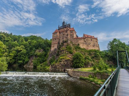 Burg Kriebstein Eine Burg auf einer Anhöhe an der ein Fluss vorbei fließt.
