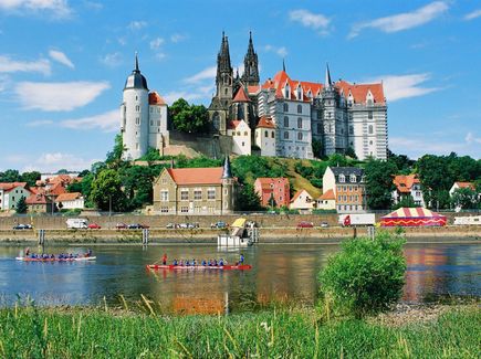 Die Albrechtsburg Meißen ist abgebildet. Vor der Albrechtsburg sind Häuser sowie der Fluss Elbe.