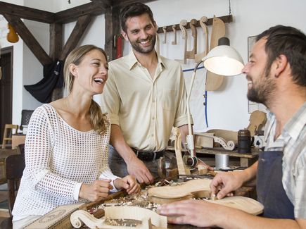 In der Instrumentenbau Schauwerkstätte in Markneukirchen unterhält sich ein Paar mit einem Instrumentenhersteller.