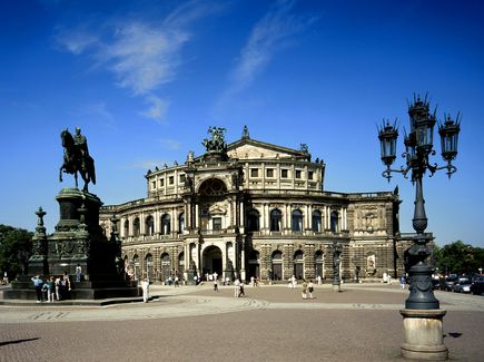 Die Semperoper in Dresden bei Tag von außen. Vor der Semperoper stehen Menschen.